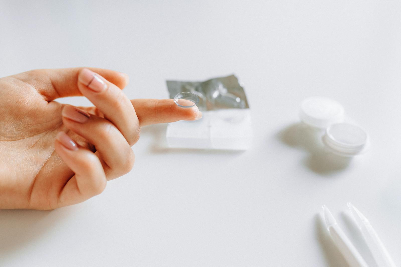A person carefully holding a contact lens on their fingertip.