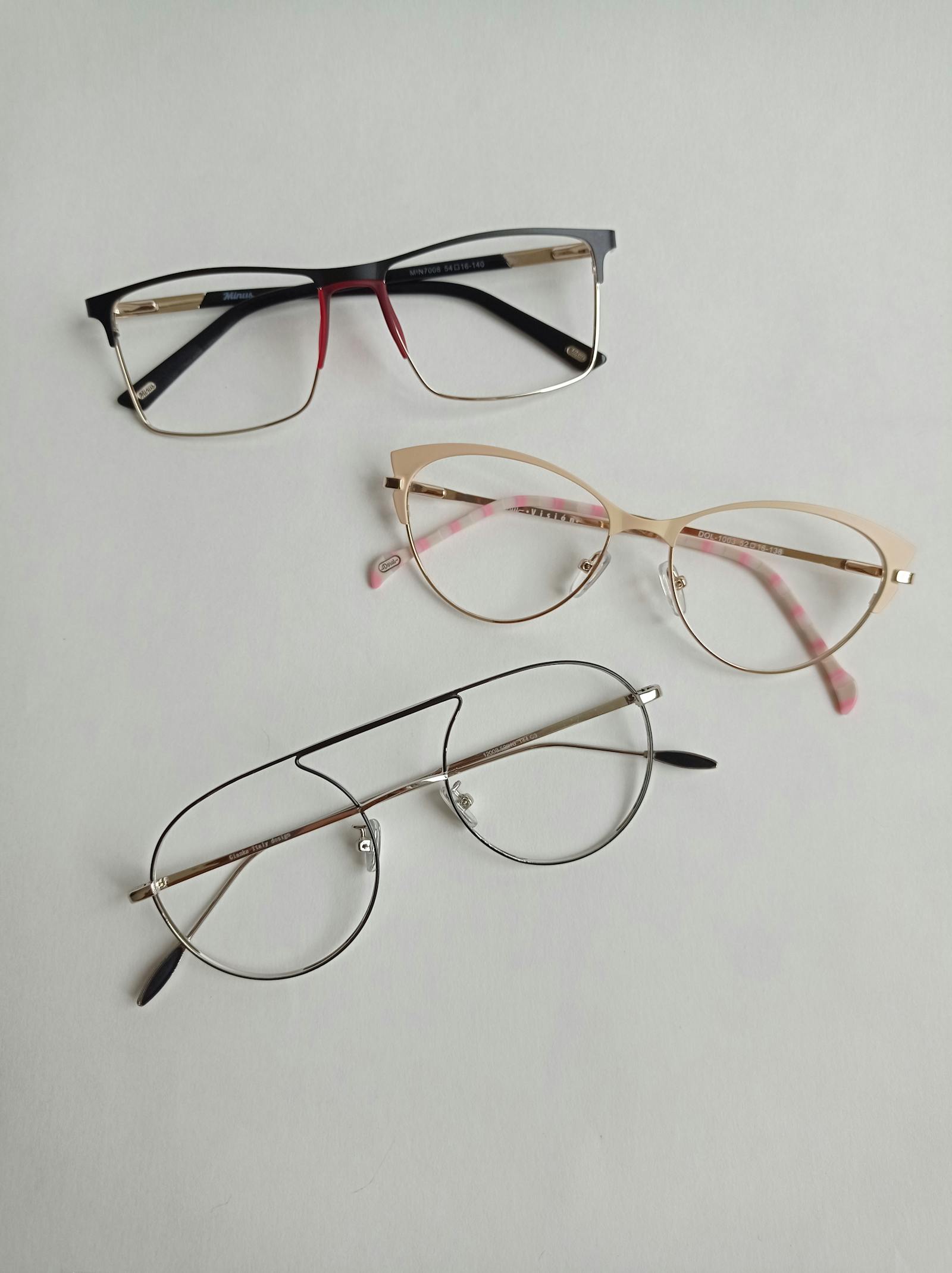 Three pairs of eyeglass frames laid out on a clean surface.