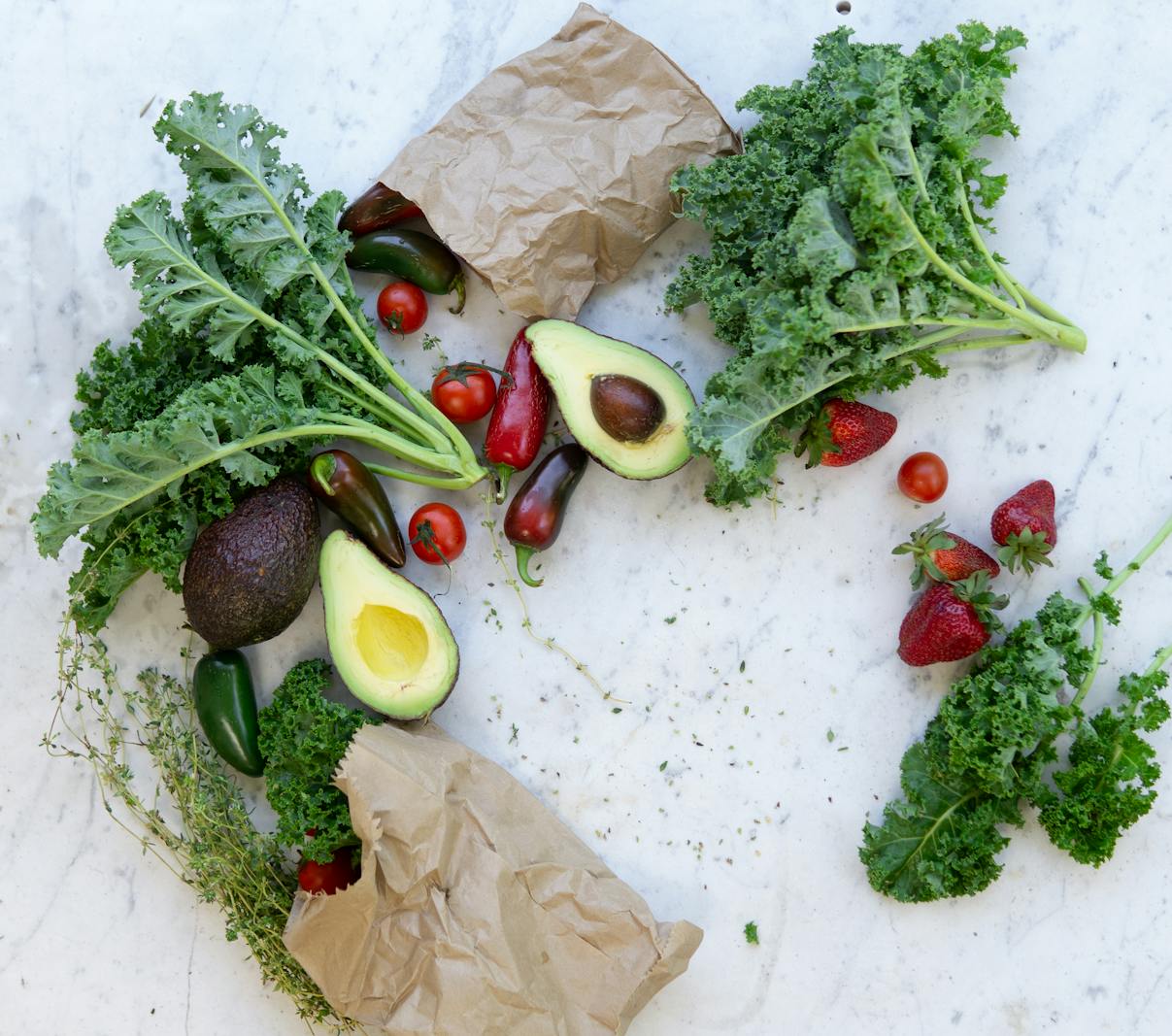 An assortment of fresh greens, berries, and oily fish on a wooden surface.